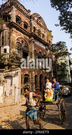 Kolkata, Westbengalen, Indien - Januar 2018: Ein Rikscha-Abzieher hart bei der Arbeit auf den Straßen mit Vintage-Architektur in der Stadt Kolkata gesäumt. Stockfoto