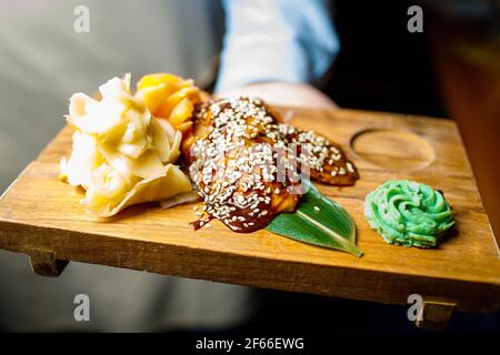 Der Kellner hält Sushi auf einem Holzbrett. Stockfoto