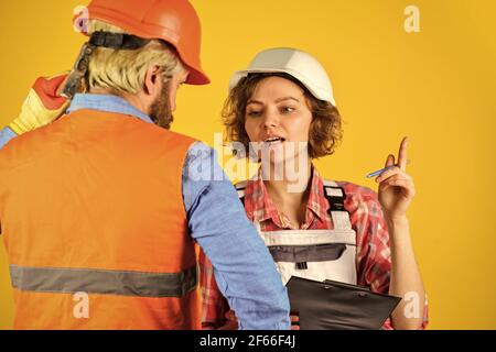 Im Bau. Blick auf Bauhausplan. Wie neues Haus gebaut wird. Arbeiter zeigen Hausentwurf. Paar diskutieren Blaupause zu Hause Stockfoto