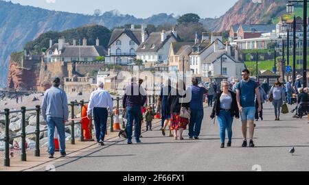 Sidmouth, Devon, Großbritannien. März 2021, 30th. Wetter in Großbritannien: Die Menschen strömen in den Badeort Sidmouth, Devon, um die herrliche Sonne zu genießen, während die Südküste vor dem Osterfeiertagswochenende in einer Mini-März-Hitzewelle sonnt. Man sah die Leute an diesem Nachmittag entlang der hübschen Esplanade spazieren gehen und die heiße Sonne im hübschen Regency Resort genießen. Kredit: Celia McMahon/Alamy Live Nachrichten Stockfoto