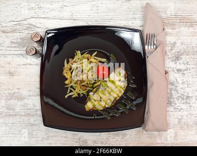Gegrillte Fischfilets mit Gemüse serviert auf Black Plate Stockfoto