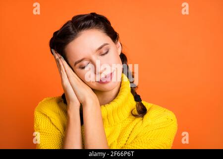 Porträt der hübschen Dame gefaltet Arme Handflächen unter dem Kopf geschlossen Augen machen Nickerchen isoliert auf orangefarbenem Hintergrund Stockfoto