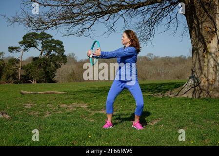 Eine Frau mittleren Alters, die Übung nimmt. Verwenden eines Pilates-Rings. Stockfoto