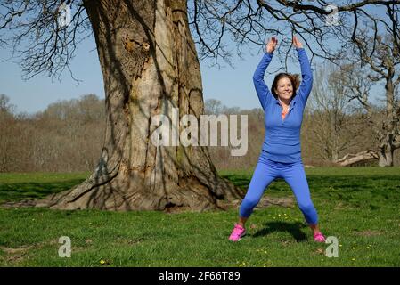Eine Frau mittleren Alters, die Übung nimmt. Sternspringen. Stockfoto