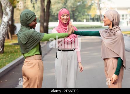 Drei Junge Muslimische Damen Geben High-Five Stehen Im Park Stockfoto