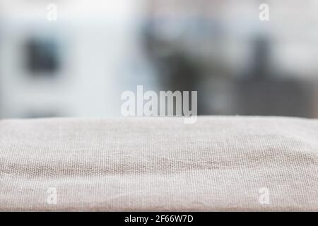 Gefaltetes rohes Naturleinengewebe auf einem verschwommenen Hintergrund für Produktpräsentation oder visuelles Layout Stockfoto