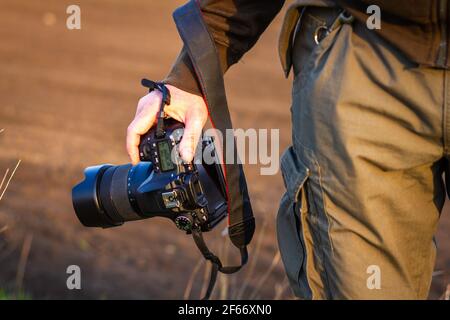 Kamera in der Hand. Fotograf hält Digitalkamera im Freien. Abenteuer in der Natur Stockfoto