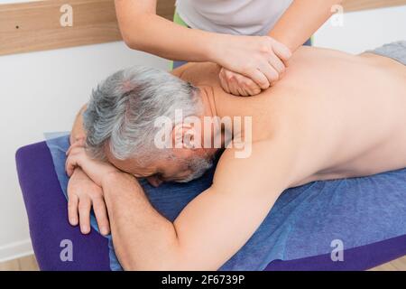 Reifer Mann immer zurück massage in Rehabilitation Zentrum Stockfoto