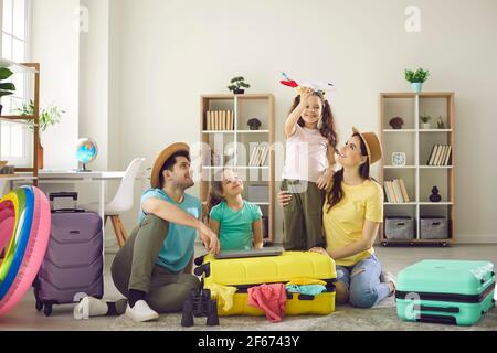 Glückliche Familie mit Kindern auf dem Boden mit verpackten Sachen Reisekoffer herum Stockfoto