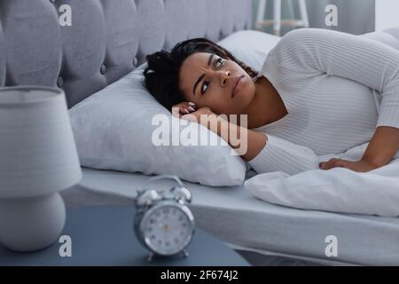 Schwarze Frau, die an Schlaflosigkeit leidet und an die Decke schaut Stockfoto