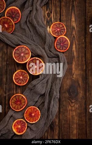 Scheiben von roten Orangen auf einem dunklen Holzhintergrund, Draufsicht. Rustikaler Stil Stockfoto