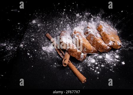 cupcake-Kekse mit Zimtstangen auf schwarzem Hintergrund mit Zuckerpulver Stockfoto