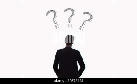 Geschäftsmann, der Fragezeichen anschaut. Ideen und Konzepte. Probleme und Entscheidungen. Stockfoto