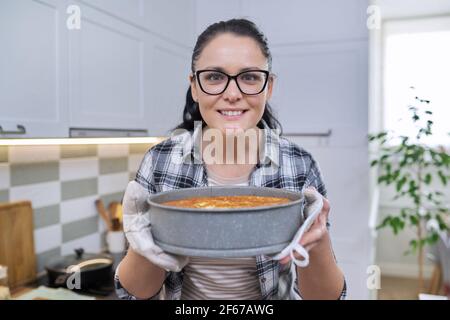 Portrait der lächelnden Frau in der Küche Fäustlinge halten heiß frisch Gebackene Apfelkuchen Stockfoto