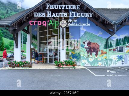 Eingang zum Gebäude des Museums und der Käsefabrik Croq Alp, Mieussy, Frankreich. Wandmalerei der alpinen Natur mit blühenden Blumen und grasenden Kühen. Stockfoto