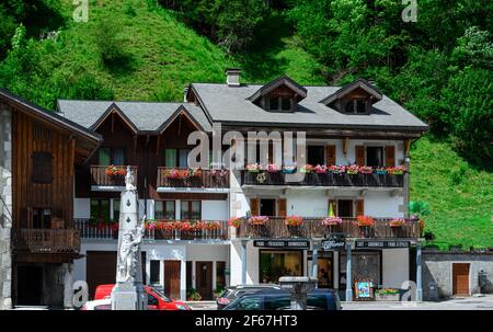 Häuser im alpinen Stil mit Balkon und farbenfroher Blumendekoration. Grünes Gras Hang im Hintergrund. Schönheit der Giffre-Bergregion, Frankreich. Stockfoto