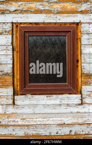 Fenster im alten Holzhaus installiert, abblätternde Farbe auf Holzbohlen, tragen Textur Stockfoto