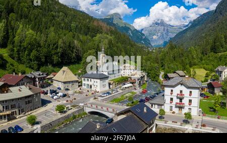 Drohnenansicht des Sixt-Fer-a-Cheval Zentrums mit Kirche und Brücke über den Fluss. Alpenkamm im Hintergrund. Schönheit der Giffre-Bergregion, Frankreich. Stockfoto