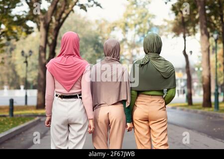 Rückansicht Von Drei Modernen Muslimischen Frauen, Die Im Park Spazieren Stockfoto