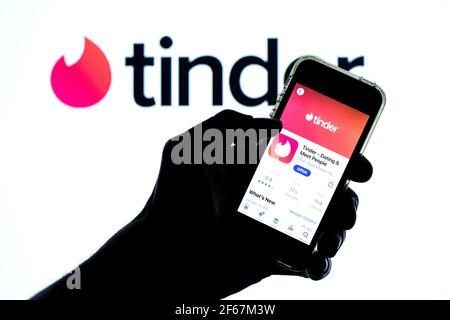 In dieser Abbildung wird die Tinder-App im App Store auf einem Smartphone-Bildschirm und im Hintergrund ein Tinder-Logo angezeigt. Stockfoto