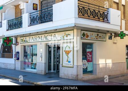 Punta Umbria, Huelva, Spanien - 21. März 2021: Spanisches offenes Apothekengeschäft. Pharmageschäft mit beleuchtetem grünen Kreuz Stockfoto