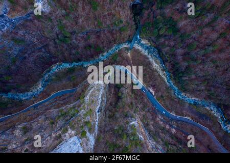 Blick von oben auf den tiefen Bergschlucht mit Straße und fließendem Fluss. Bäume an steilen Felswänden der Schlucht, Vercors, Frankreich. Stockfoto