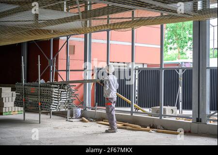 Bauarbeiter in Latzhose Manipulation mit einem Teil des Gerüsts. Verkehrsinfrastruktur Baustellenkonzept. Stockfoto