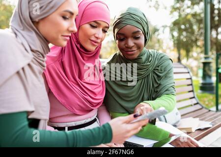 Muslim Female Zeigt Pädagogische Anwendung Auf Smartphone, Um Freunde Im Freien Stockfoto