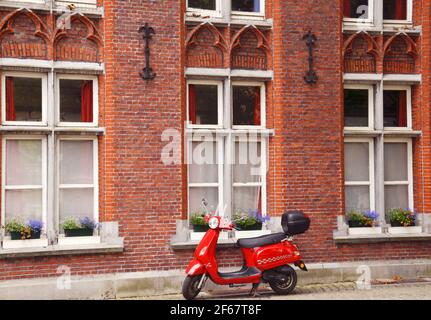 BRÜGGE, BELGIEN, EUROPA,1ST. JULI , 2017. Ein wunderschöner roter Oldtimer-Roller, der vor einem schönen Haus in den Straßen von Brügge, BELGIEN, geparkt wurde Stockfoto