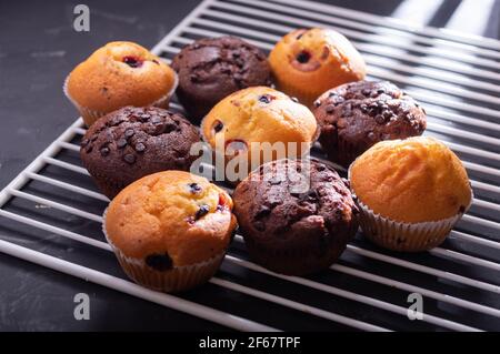 Viele verschiedene Muffins auf dem Küchengrill. Schokoladen- und MilchMuffins. Stockfoto