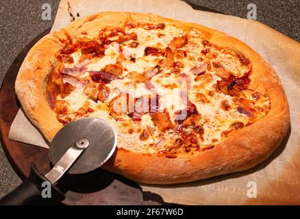 Eine frisch aus dem Ofen hausgemachte Grill Huhn Pizza bereit, mit Schneidrad geschnitten werden. Stockfoto