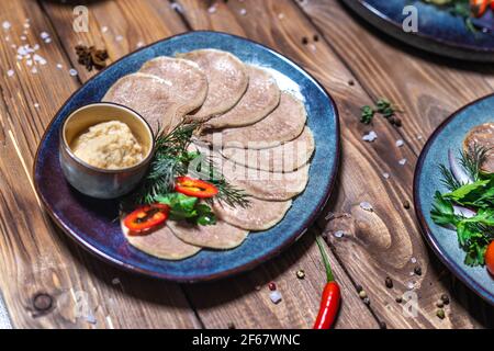 Fleisch- und Wurstaufschnitt, Knoblauch, Chilischoten, Tomaten und andere Gewürze auf einem braunen Hintergrund. Restaurant-Service. Stockfoto