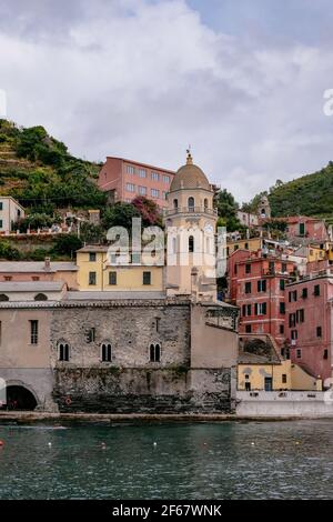 Schöner Naturhafen mit bunten traditionellen Häusern und Santa Margherita di Antiochia Kirche und Turm - Vernazza, Cinque Terre, Italien Stockfoto