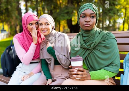 Muslimische Dame Hört Frauen Zu, Die Im Freien Hinter Dem Rücken Flüstern Stockfoto