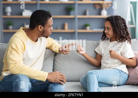Serious schwarzen Vater schimpft seine zornige Tochter, Haus innen Stockfoto
