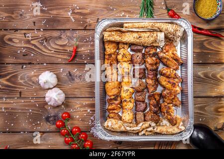 Shish Kebab und lula Kebab werden in einen Behälter gegeben. Lieferung von Lebensmitteln aus Restaurants. Stockfoto