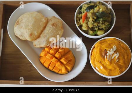 Puri serviert mit Mangopellstoff und Kartoffelmasala. Lokal bekannt als puri Masala und Aamras. Beliebte nordindische Küche im Sommer. Stockfoto