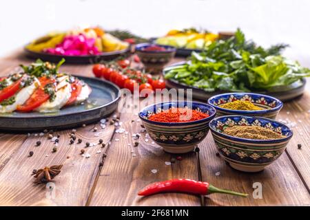 Tomaten mit Mozzarella, frischen Kräutern, Chilischoten, Gewürzen im Sortiment auf Holzhintergrund. Speisekarte im Restaurant. Stockfoto