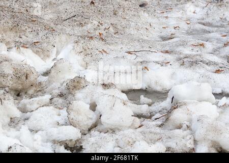 Früher Frühling schmutziger grauer geschmolzener Schnee mit Sandmuster Textur Nahaufnahme Grunge Hintergrund Stockfoto