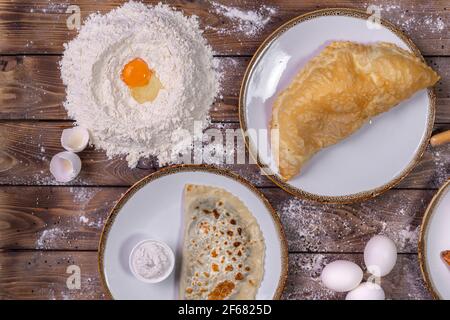 Die Käsereien auf dem Teller, die Soße, das Mehl, die Hühnereier auf dem braunen hölzernen Hintergrund. Flaches Layout. Stockfoto