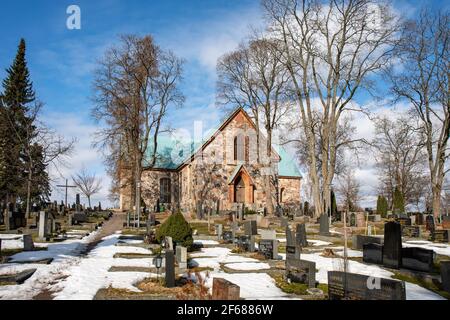 Mittelalterliche St. Michaels graue Steinkirche und Kirchhof mit Grabsteinen in Kirkkonummi, Finnland Stockfoto