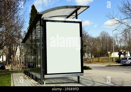 Bild Composite. Bus-Schutz & Bushaltestelle. Leere Licht weiße Box. Glasstruktur. park-ähnliche städtische Einstellung. Grüner Hintergrund. Plakatwand und Plakatwand Stockfoto