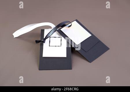 Makro-Mock-up leeres schwarz-weißes Papier-Tag mit Schwarz-weißes Satinband für Markenlogo auf Grün Baumwollmaterial Stockfoto