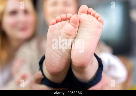 Die ganze Familie, Eltern und Kinder halten die Fersen des Babys in den Handflächen. Stockfoto