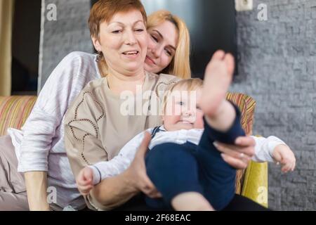 Die ganze Familie, Eltern und Kinder halten die Fersen des Babys in den Handflächen. Stockfoto