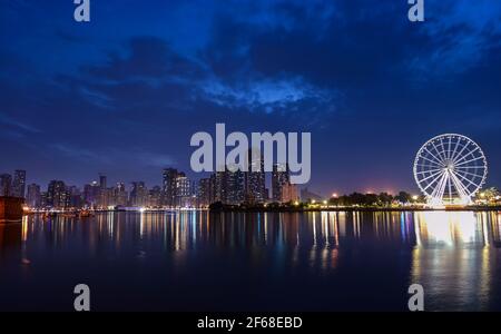 Panoramablick auf die Wolkenkratzer von Sharjah und die Vergnügungsfahrten im Montazah-Park, aufgenommen vom Majaaz-Park in Sharjah, VAE. Stockfoto