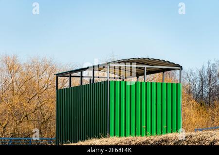 Eine öffentliche Bushaltestelle von einem grünen Metallprofil an Ein Frühlingstag Stockfoto