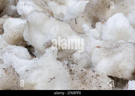Früher Frühling schmutziger grauer geschmolzener Schnee mit Sandmuster Textur Nahaufnahme Grunge Hintergrund Stockfoto