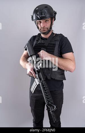 Voll ausgestattet für Airsoft männlich Blick auf die Kamera und trägt Helm und Schutzweste. Kampf mit hoher Präzision Krieger macht das Spiel groß Stockfoto