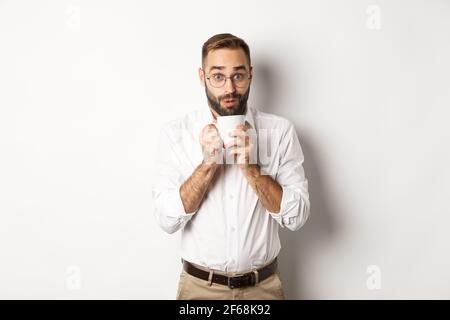 Glückliche Büroangestellte trinken heißen Kaffee und schauen aufgeregt, Klatsch, stand über weißem Hintergrund Stockfoto